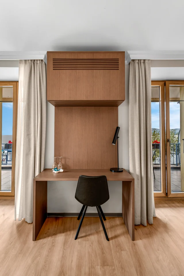 Le bureau sur mesure en bois entre les deux fenêtres de la chambre