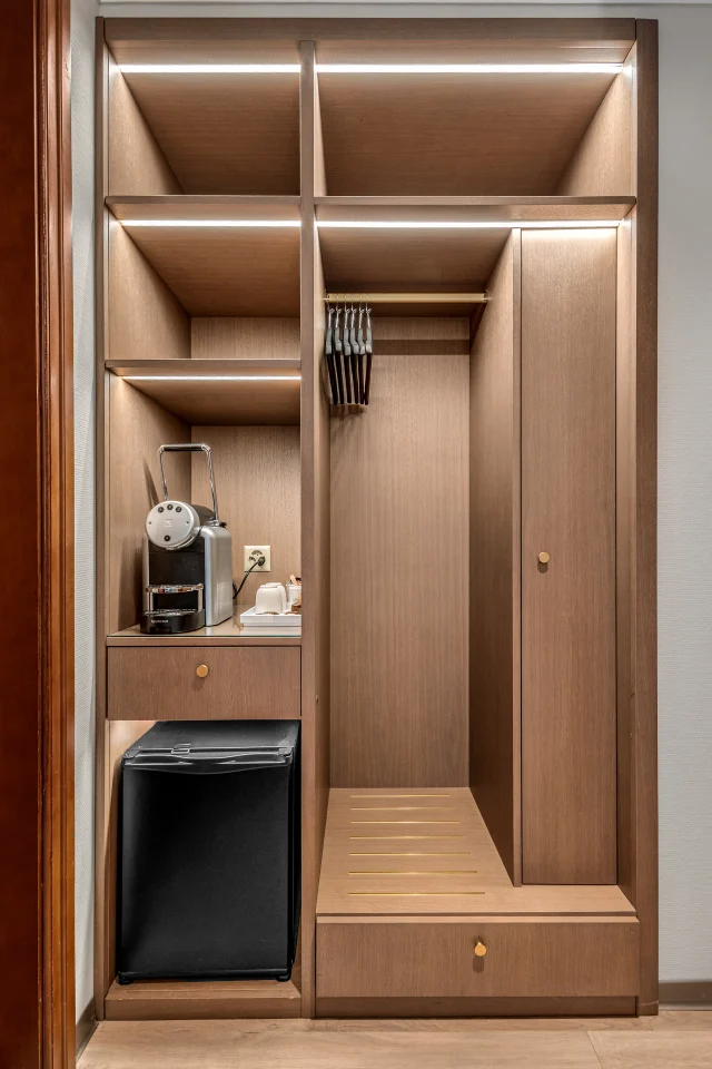 La penderie ouverte et éclairée, avec ses étagères et son minibar intégré
